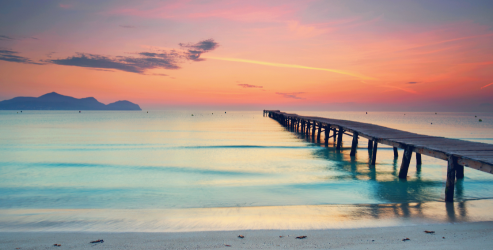 A serene beach scene at sunset with a wooden pier extending into calm waters, symbolizing reflection, connection, and the essence of love.