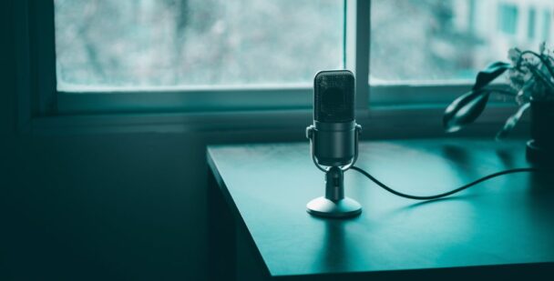 A podcast microphone by the window in teal tones, representing honest conversations and presence.